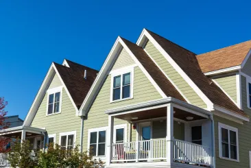 light green craftsman home with gabled dormers and covered front porch