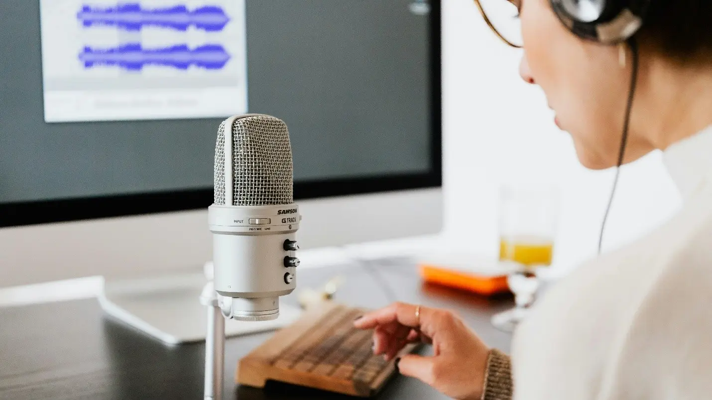 Person recording voiceover using studio microphone and audio waveform software