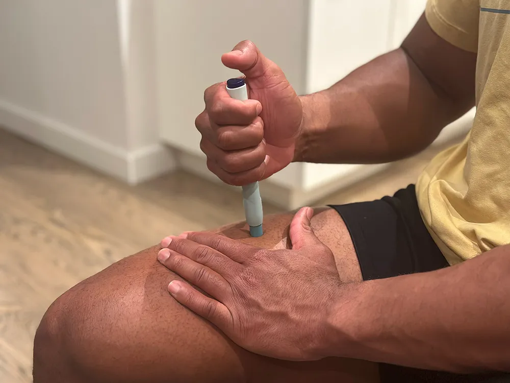 Man injecting self with auto-injector on thigh