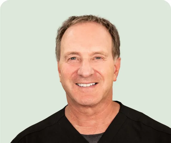 Smiling middle-aged man with short brown hair wearing a black shirt against a light background.