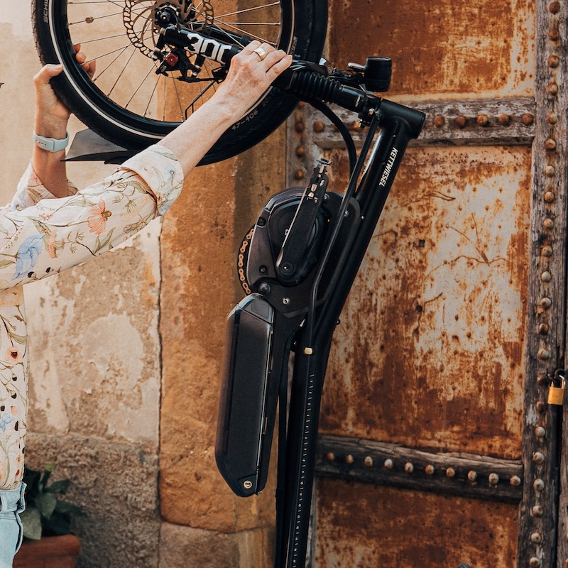 Kettwiesel ONE von Hase Bikes wird von einer Frau aufrecht geparkt