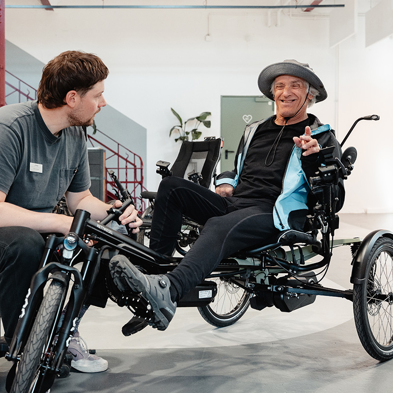 Beratung im Schaltwerk von Hase Bikes ein Mann sitzt auf einem Dreirad für Erwachsene Kettwiesel ONE