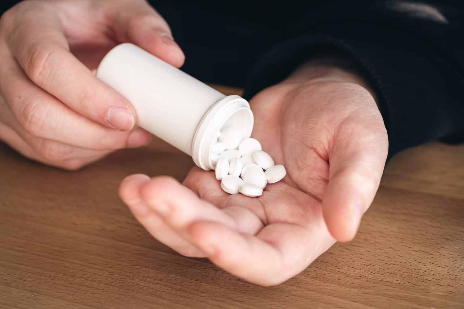 A lot of white pills in the hands of an adult man