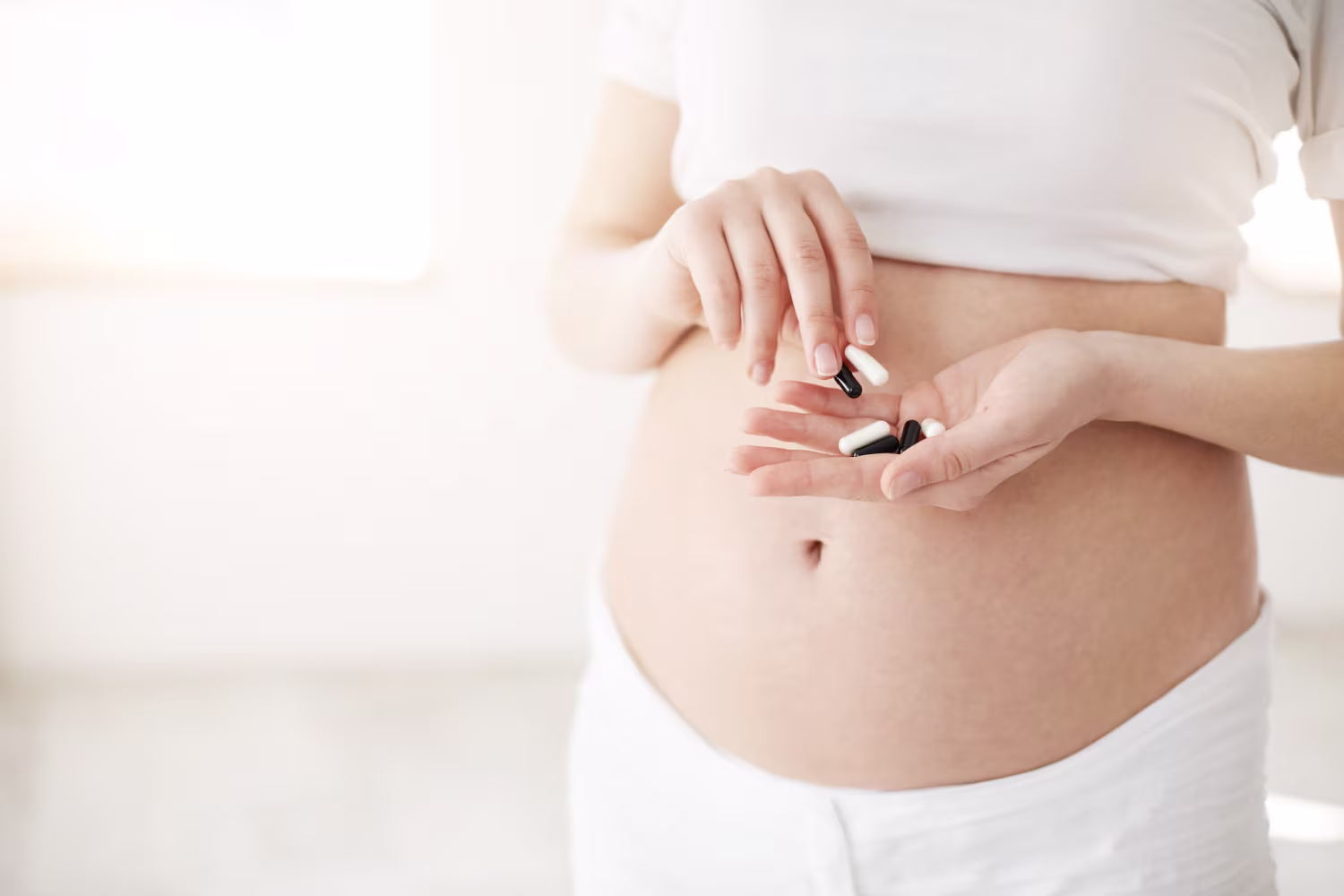 Closeup of pregnant soon to be mother holding antihistamines pills