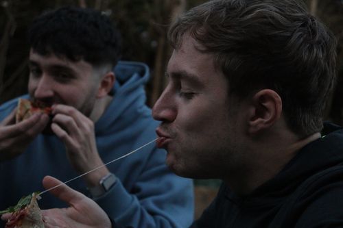 A little boy eating a big pizza and drinking water