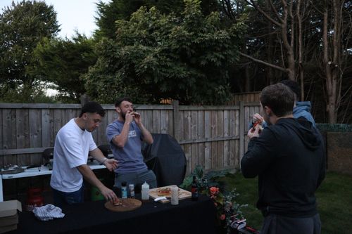 Two guys busy in the kitchen preparing pizza
