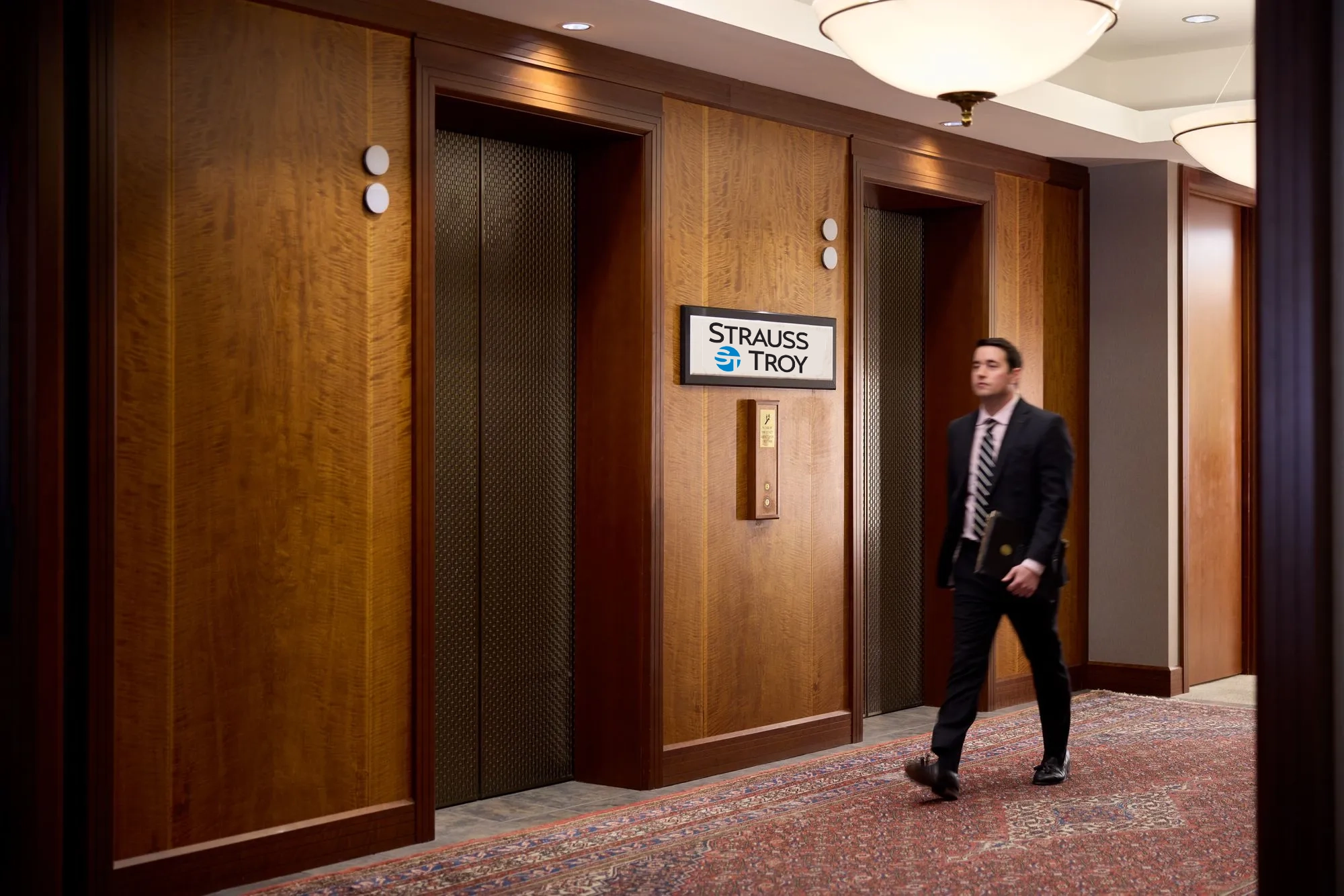 Strauss Troy Attorney walking past elevator bank in law office.