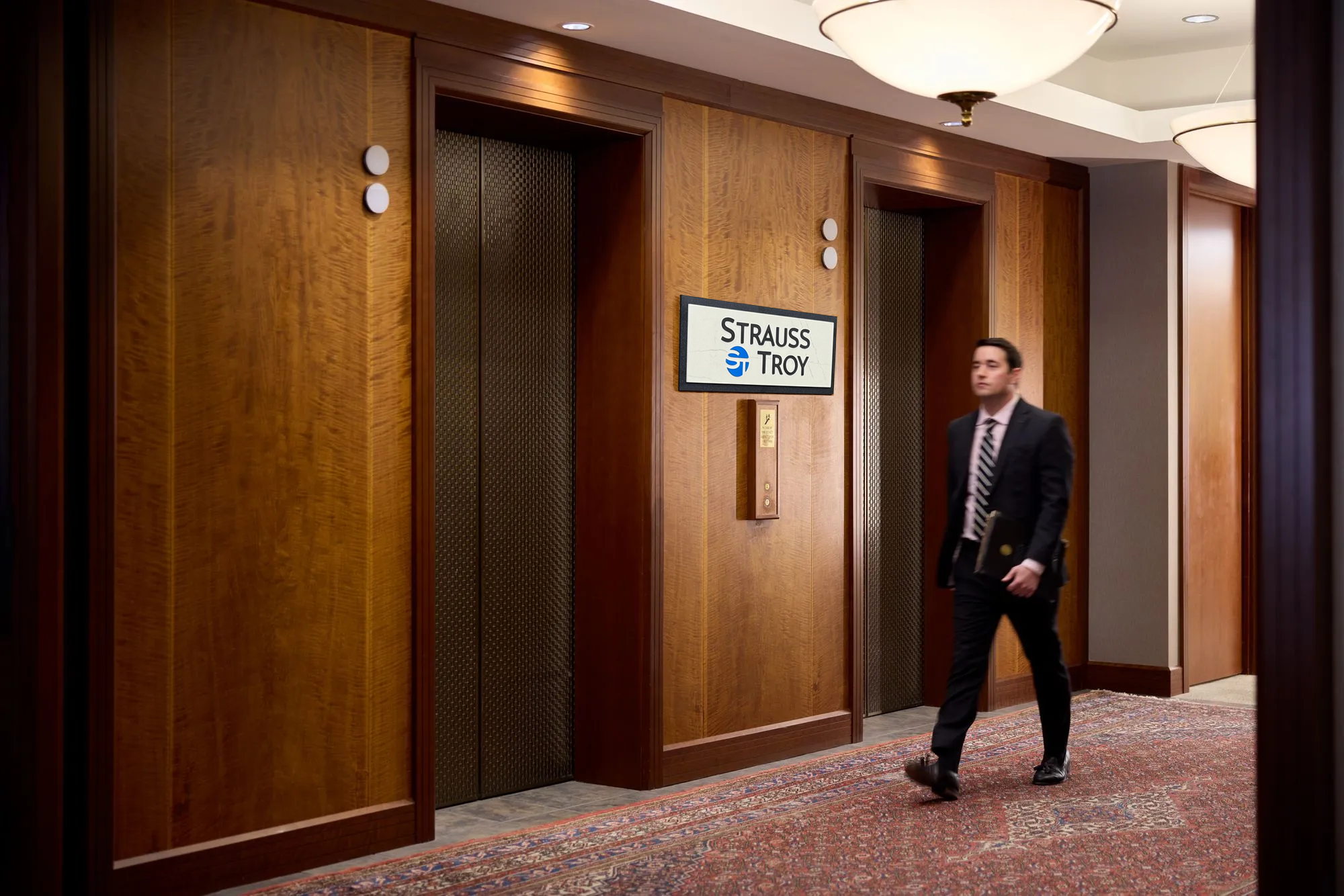 Strauss Troy Attorney walking past elevator bank in law office.