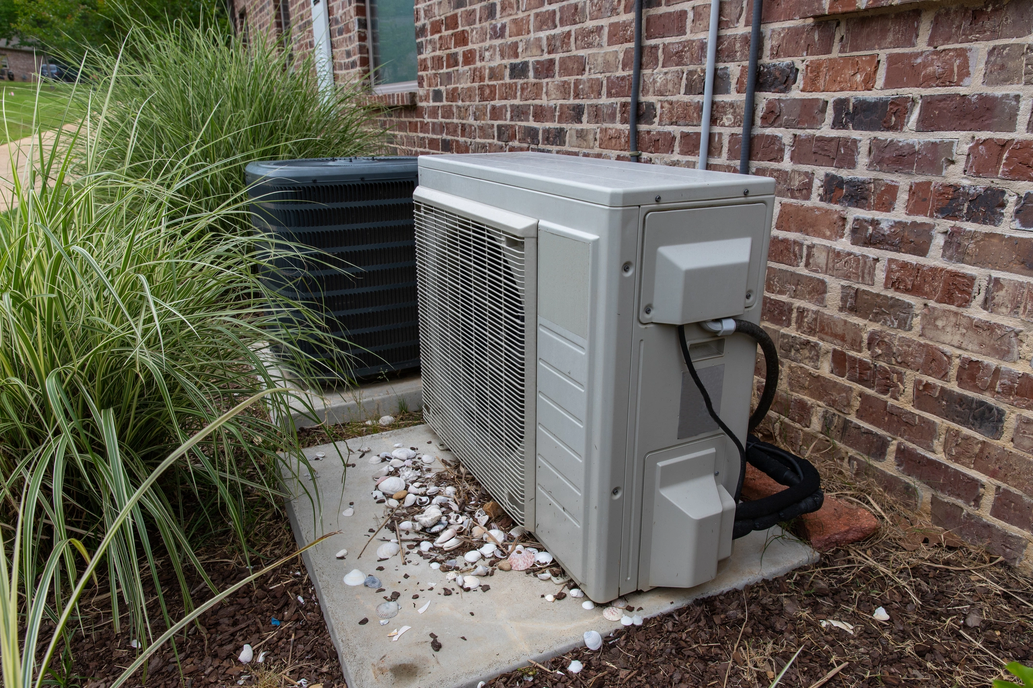 Air conditioning units on concrete slabs outside a brick building,