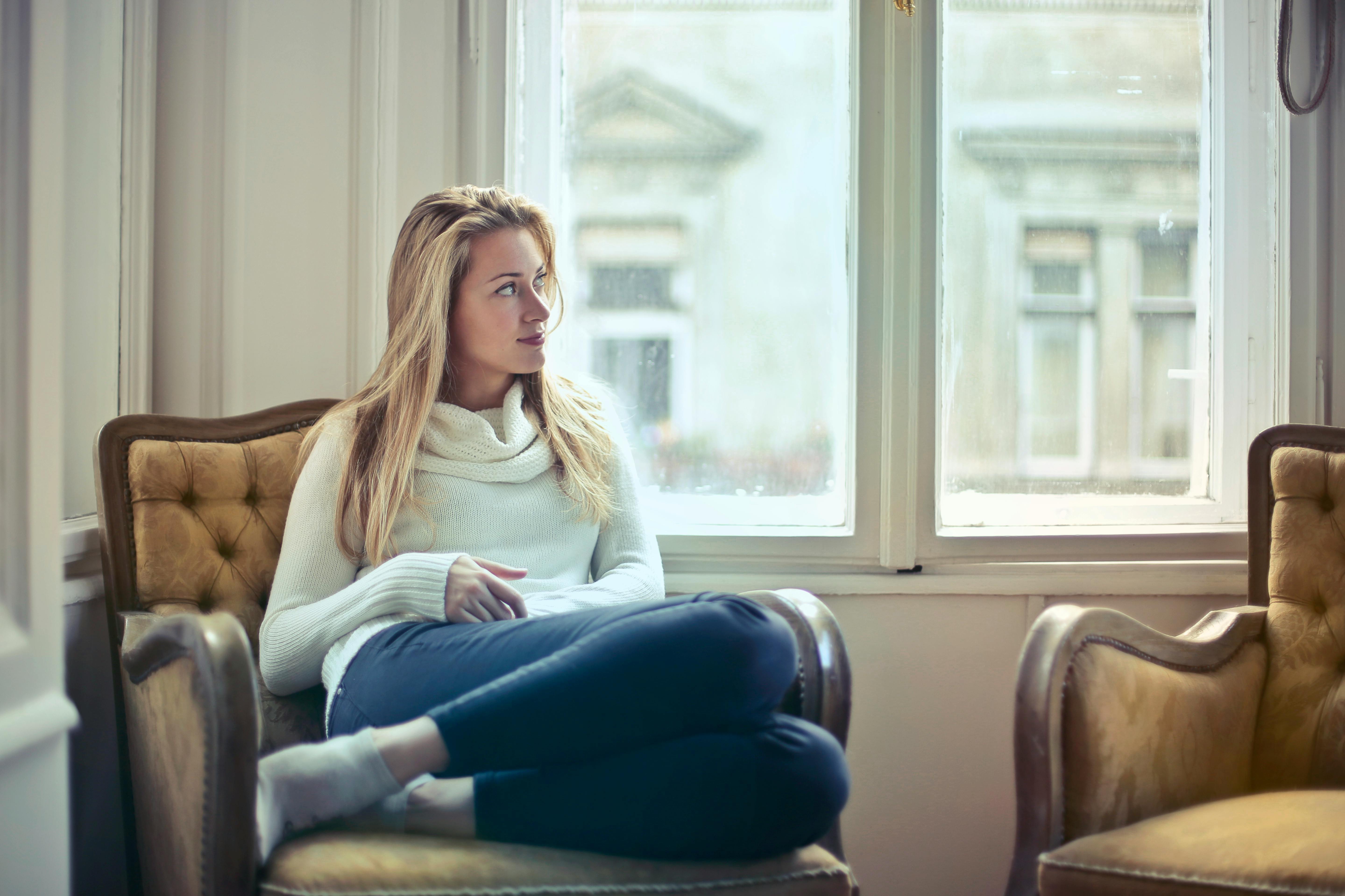 Woman seated in a vintage armchair gazing through a window
