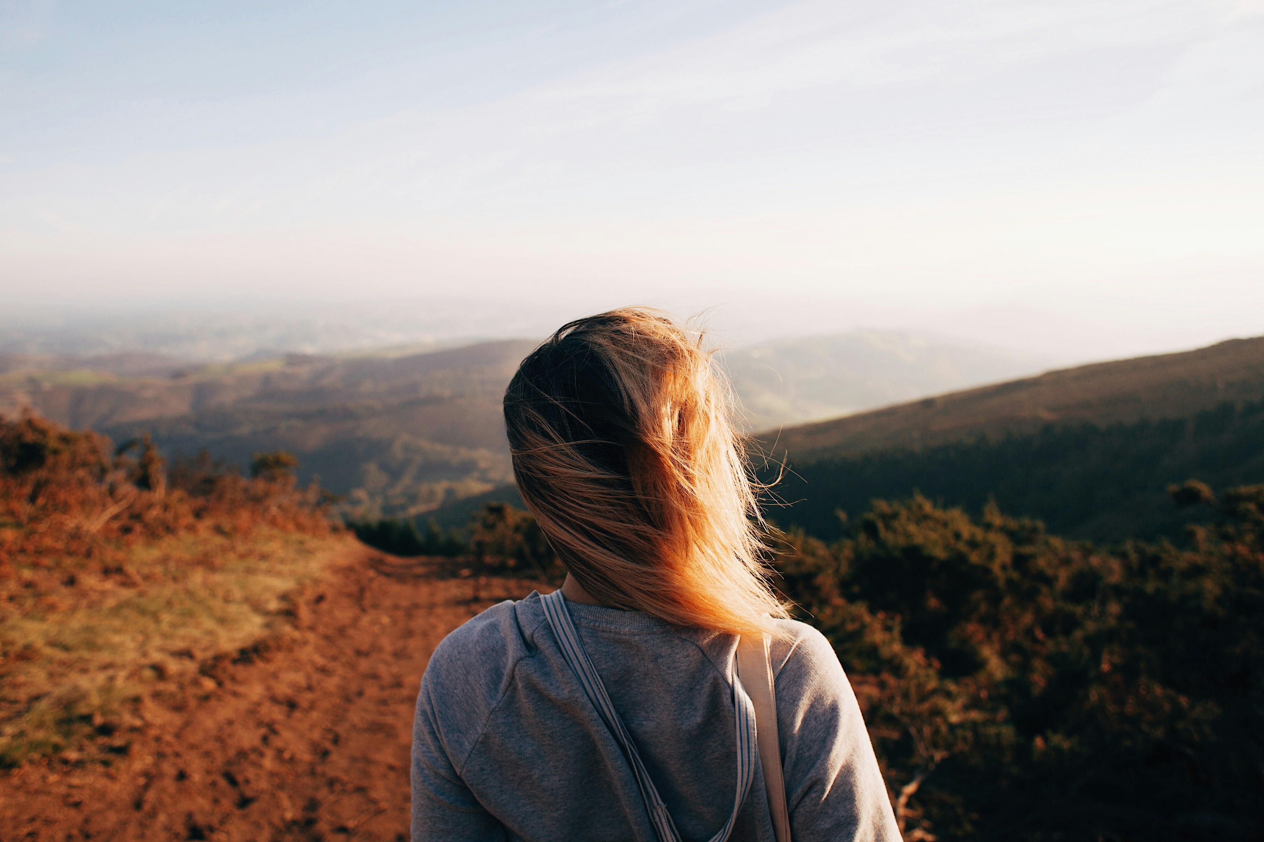 Woman on a sunset hiking trail with wind blowing through her hair