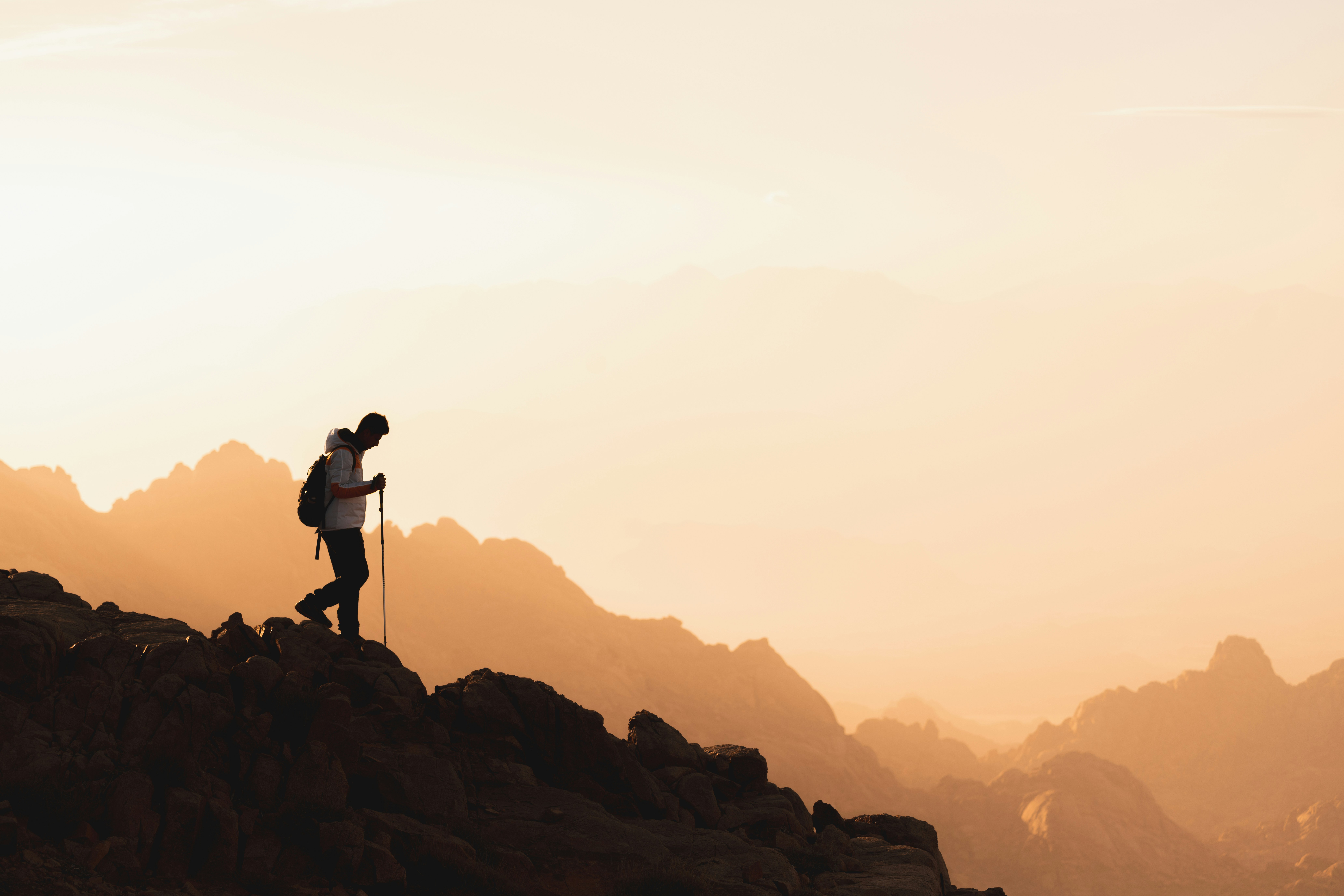 Hiker descending a mountain trail in profile at sunset