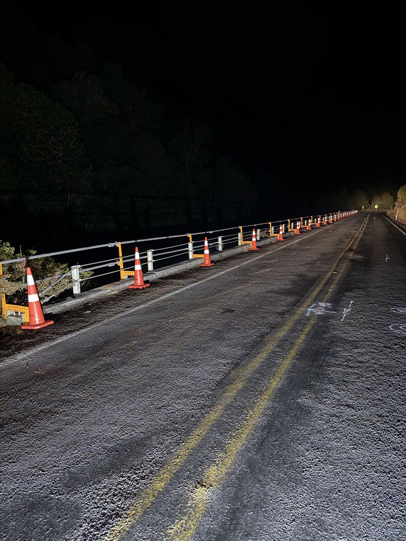 Roadside guardrail run lit up at night with road cones