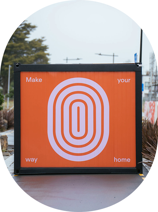 Orange shipping container with a pink concentric oval design and the words 'Make your way home' in each corner.