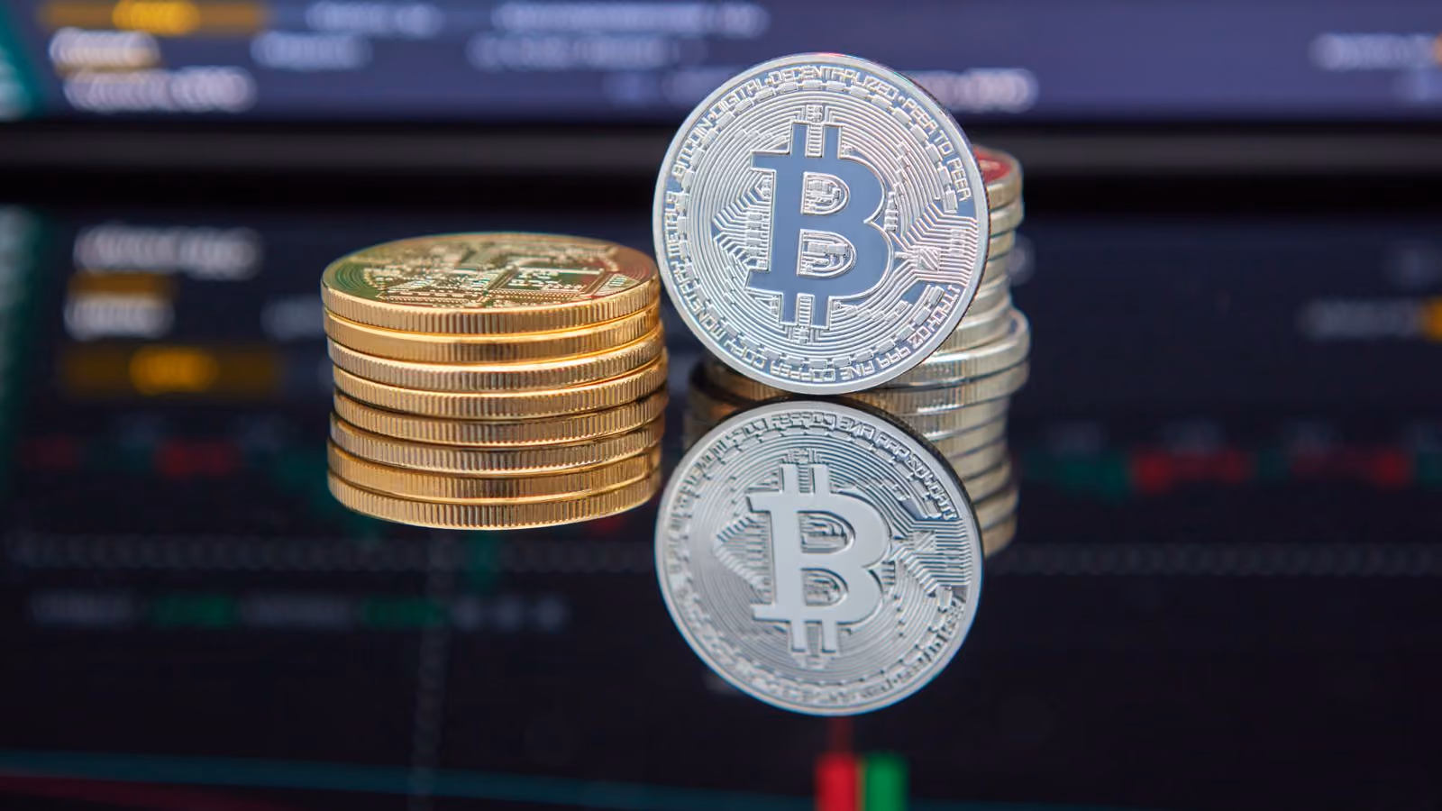 Monedas de bitcoin frente a una pantalla con gráficos de mercado, ilustrando la reacción del mercado cripto