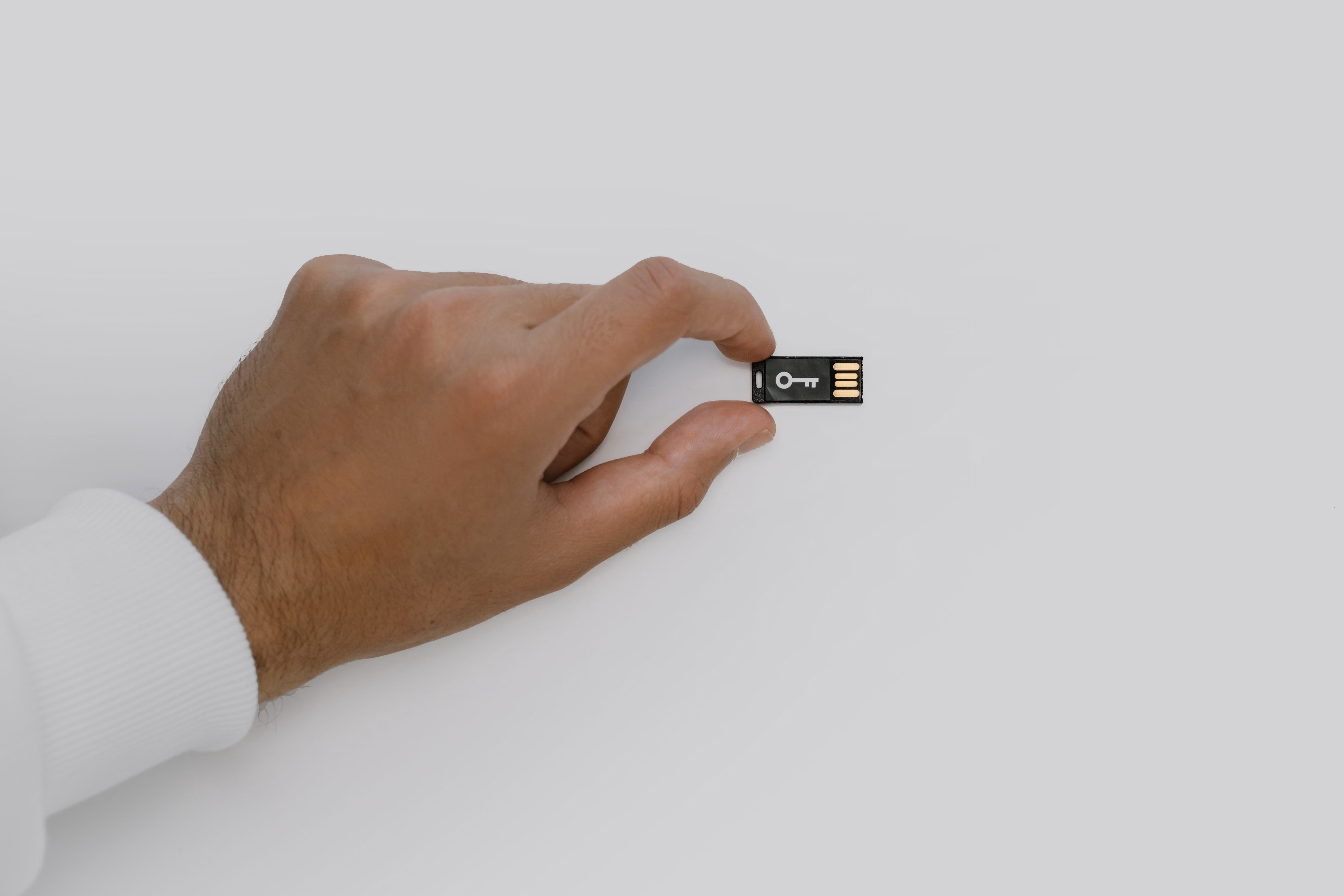 Mano sosteniendo una llave USB con símbolo de llave, representando la seguridad de las claves privadas de una hardware wallet de Bitcoin
