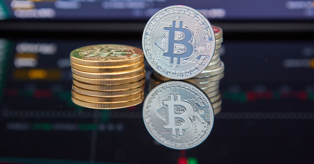 Monedas de bitcoin frente a un gráfico de trading de criptomonedas