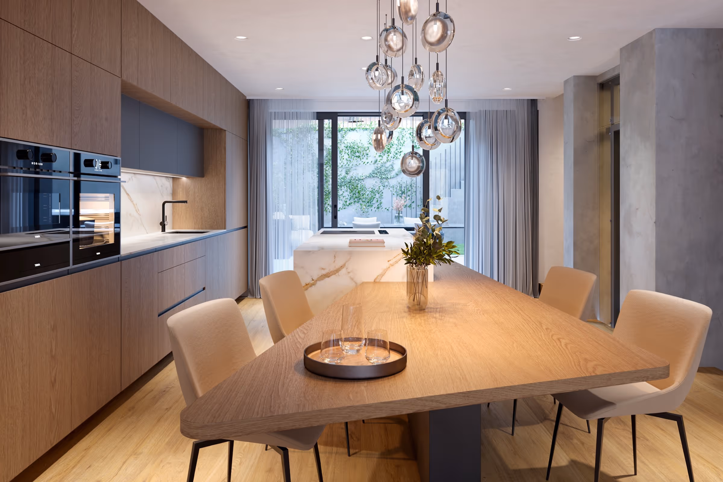 Modern kitchen with wooden cabinetry, marble island, dining table with chairs, and hanging glass pendant lights.