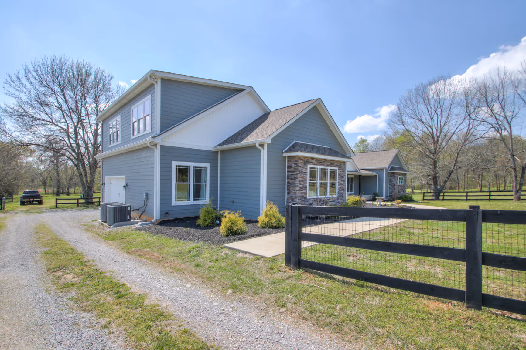 A single-story blue house with a fenced yard, showcasing a listed home for sale through The Hubner Group.