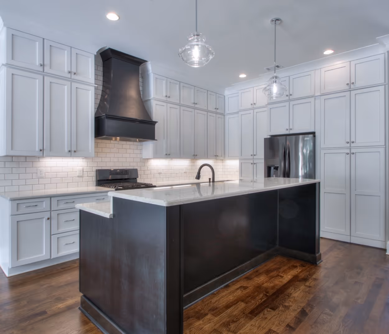 A modern kitchen with white cabinetry and a sleek design, showcasing a completed home construction project.