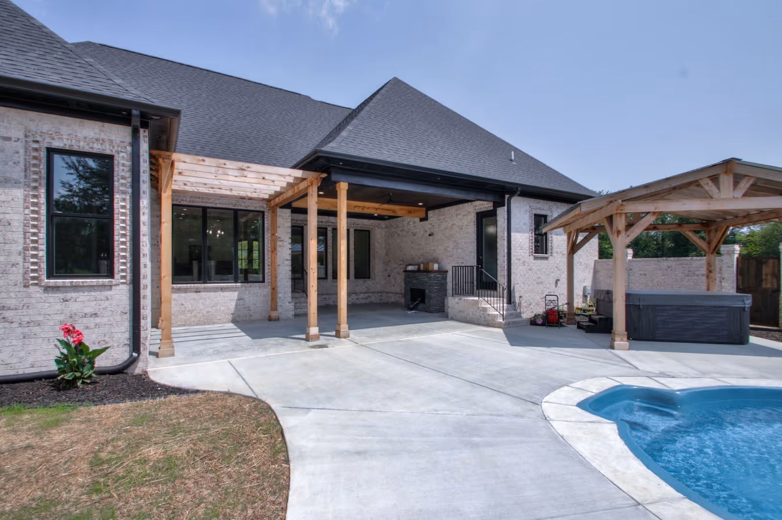 A newly constructed outdoor living space with a covered patio and wooden pergola, showcasing The Hubner Group’s craftsmanship in exterior home projects.