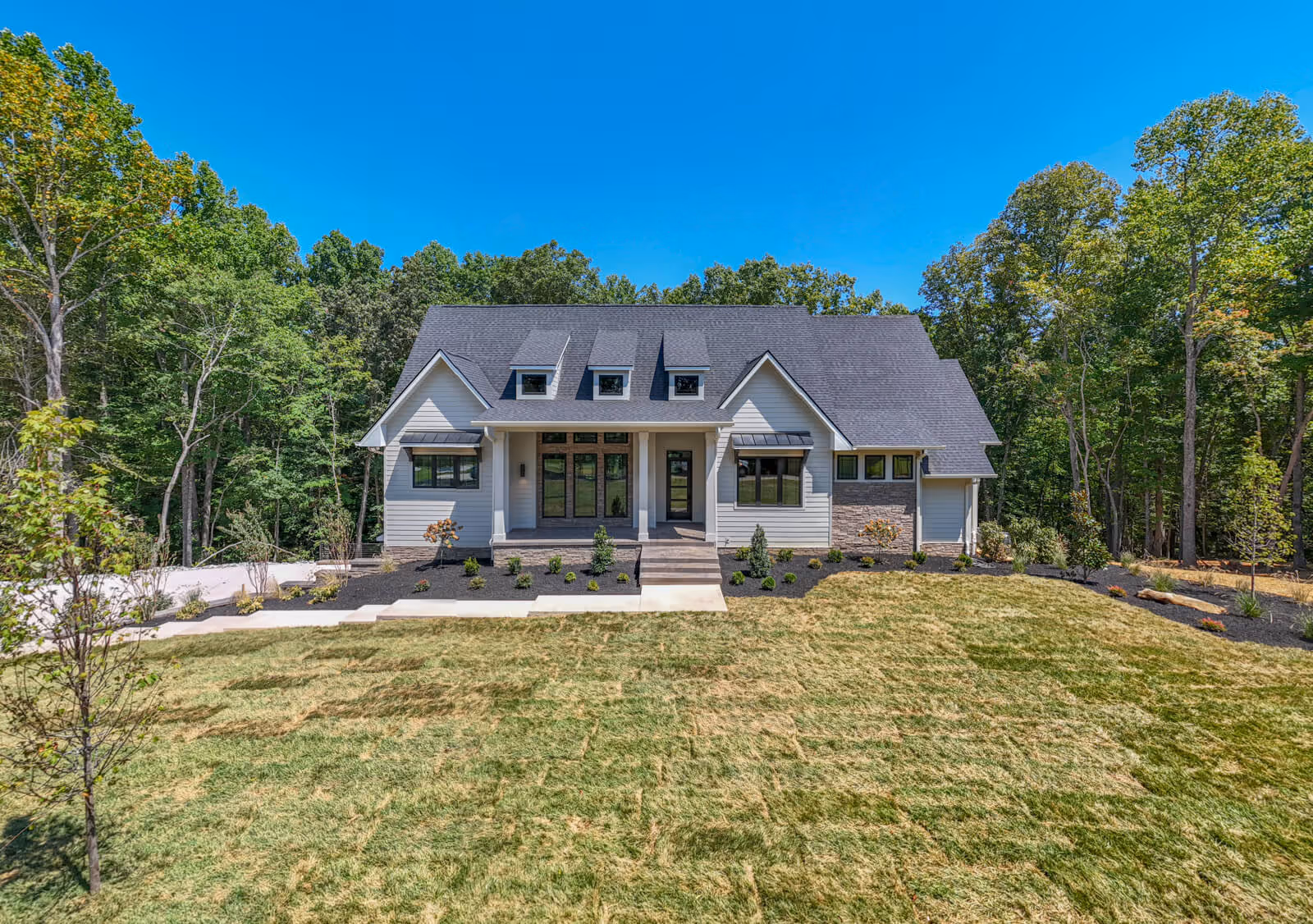A large luxury home with a spacious front yard, surrounded by trees.