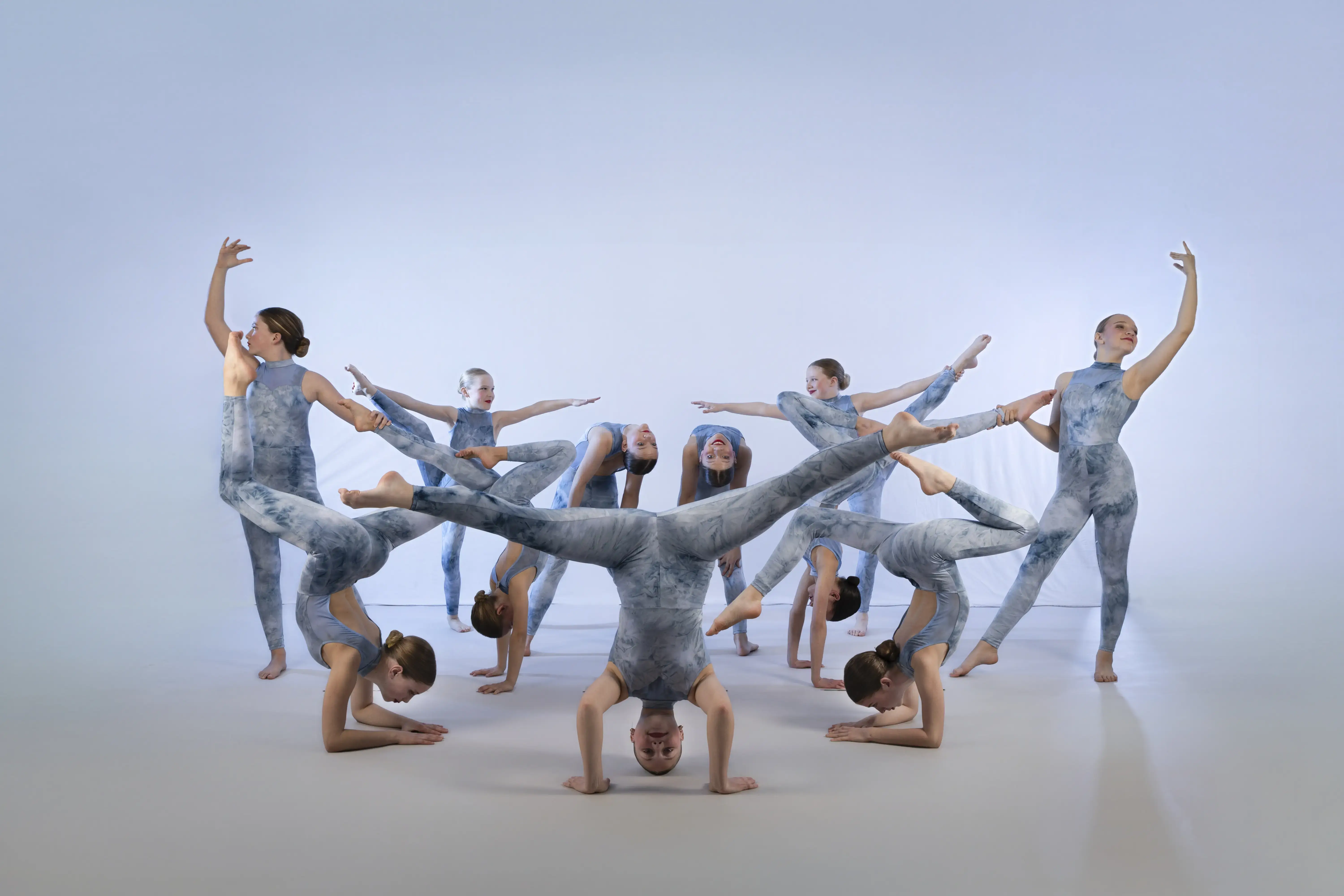 Dancers from the Abba group at The SPACE Inc posing in their sparkling sequinned ruffled blue costumes on a black background.