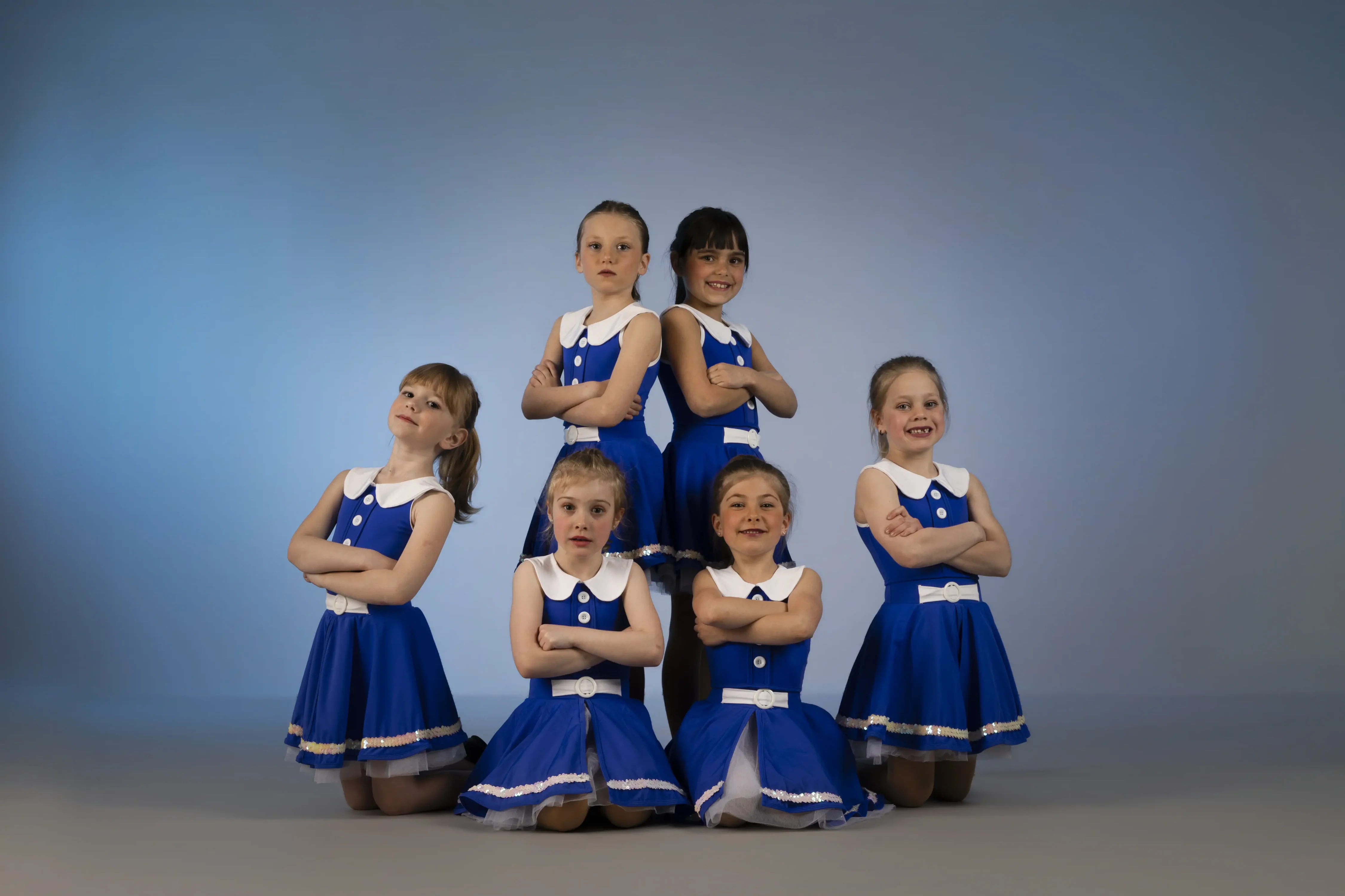 Dancers from the Abba group at The SPACE Inc posing in their sparkling sequinned ruffled blue costumes on a black background.