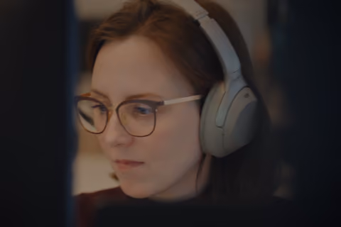 DualEntry employee wearing headphones focused on her screen in a careers video still