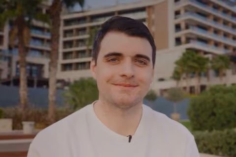 DualEntry employee in a white tee speaking outdoors near palm trees