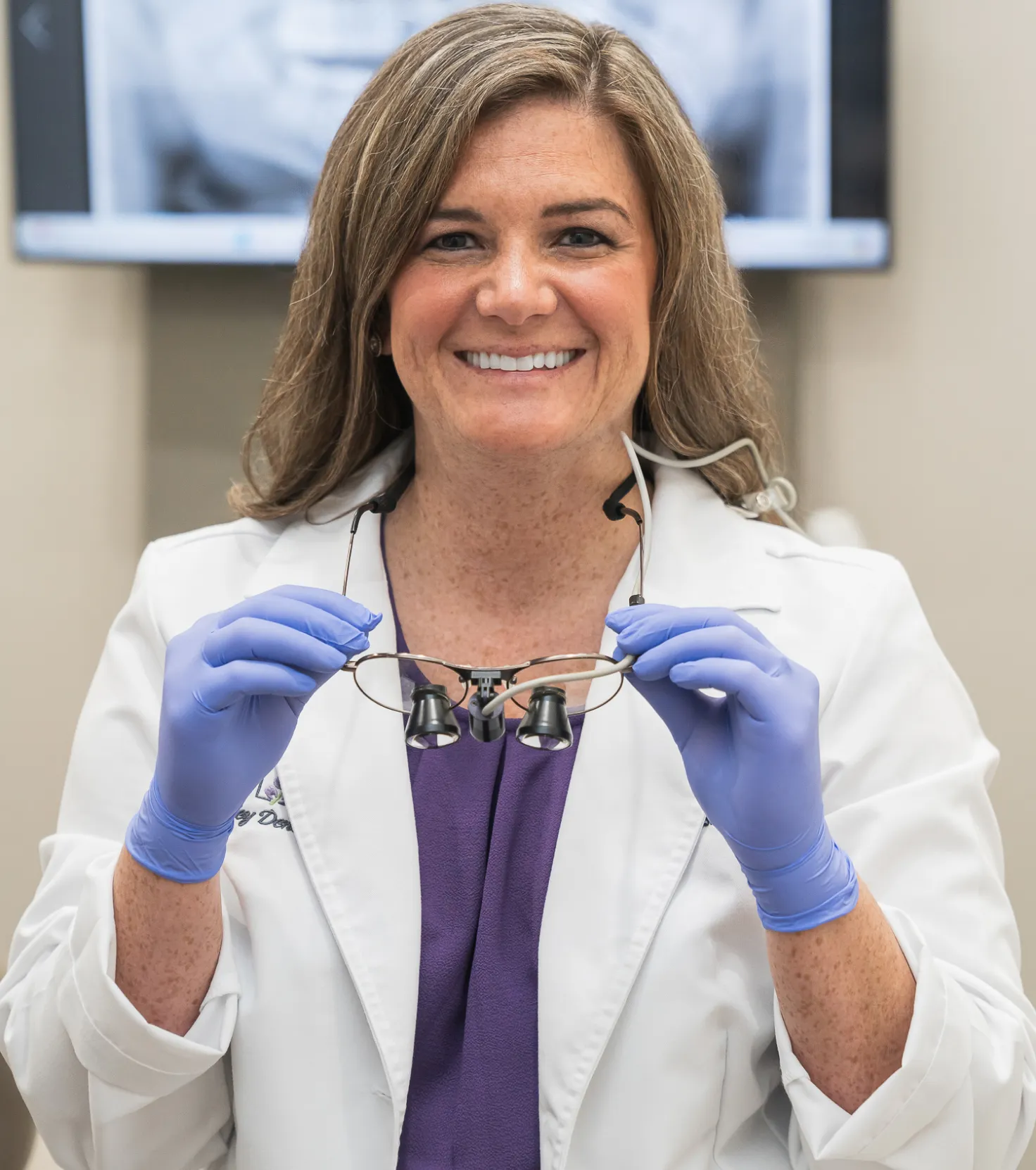 Dr. Hensley smiling puttiog on ther glasses.