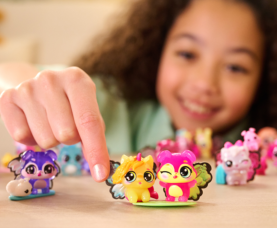 A dark curly haired girl plays with an assortment of different Bloomables figurines