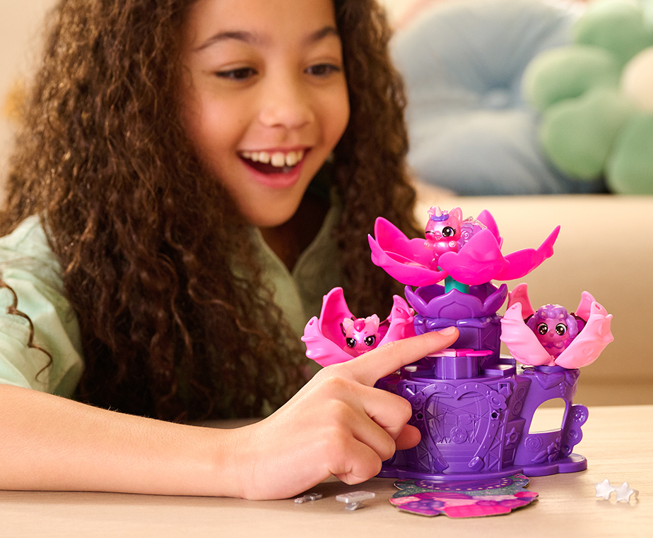 A dark curly haired girl smiles as she plays with the Flower Fest toy