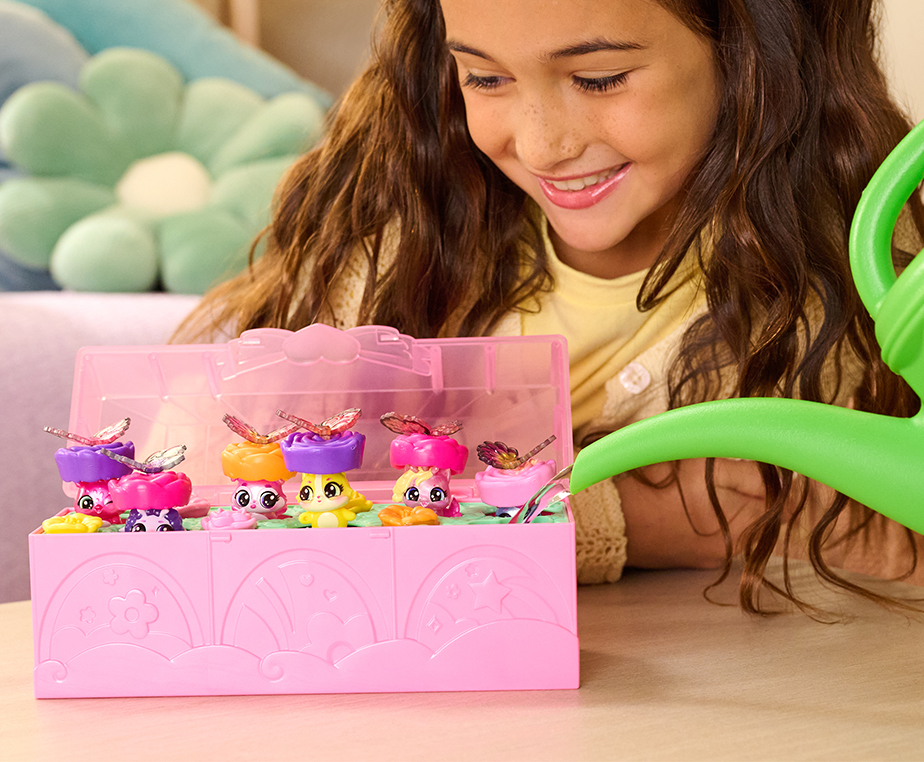 A Caucasian girl uses a green watering can to water the Bloom Bash toy