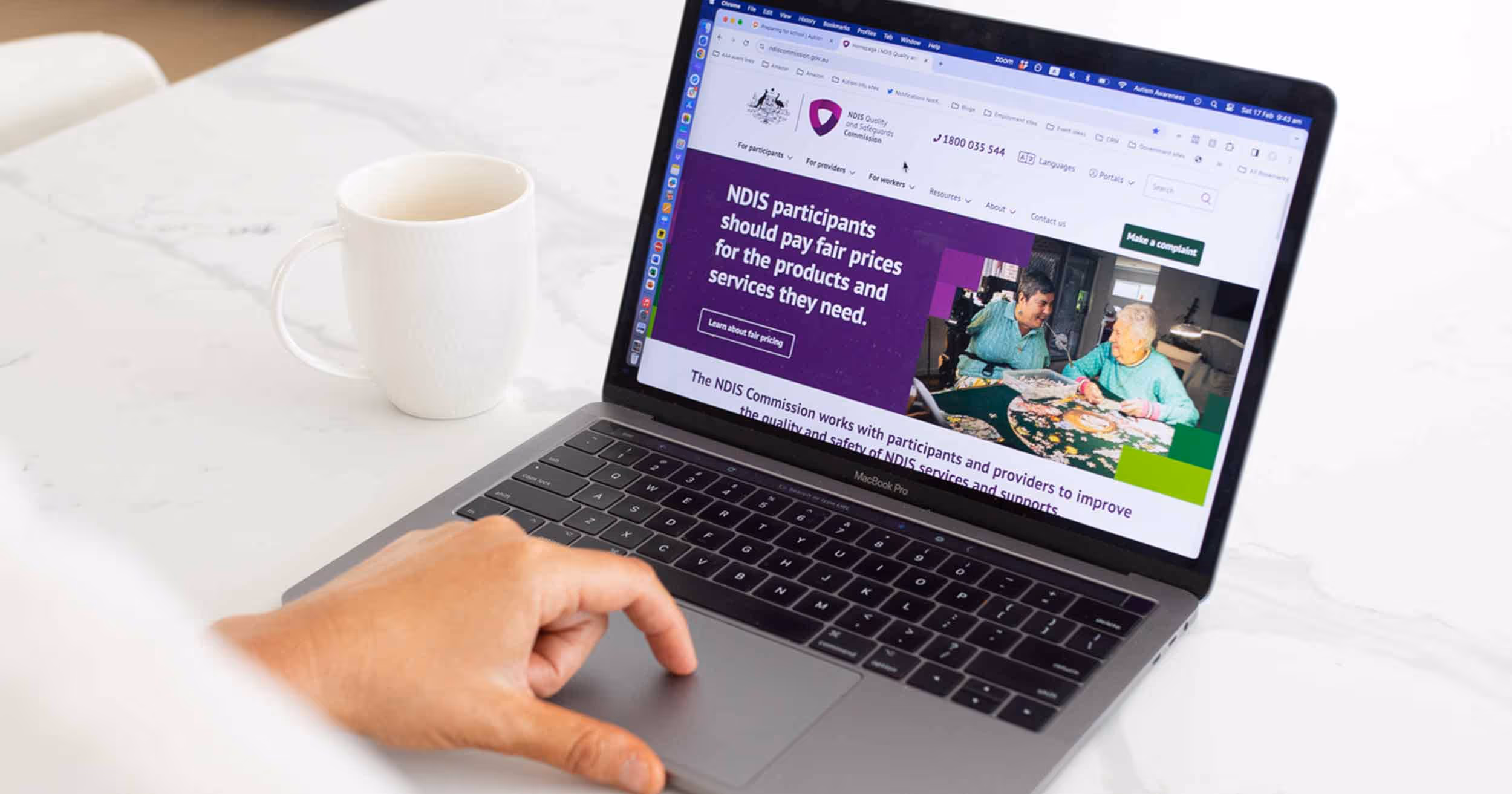 laptop on table with hand on the keyboard - NDIS website is on the screen