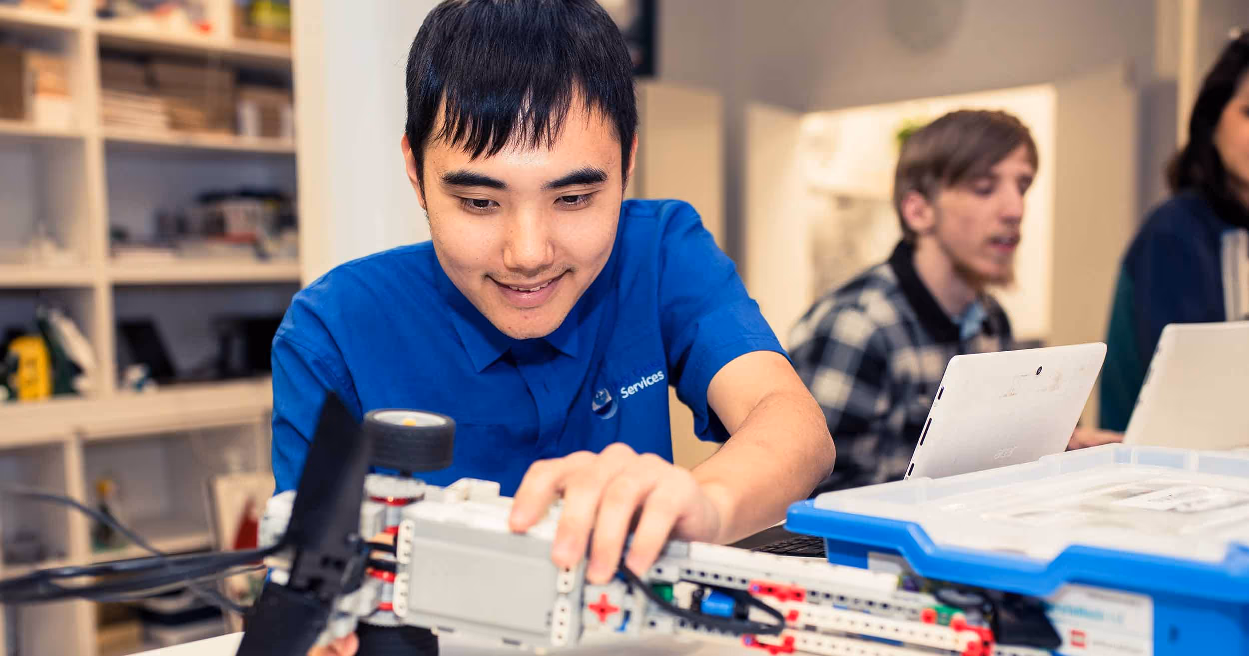 Young asian man in workshop building mechanical vehicles and smiling