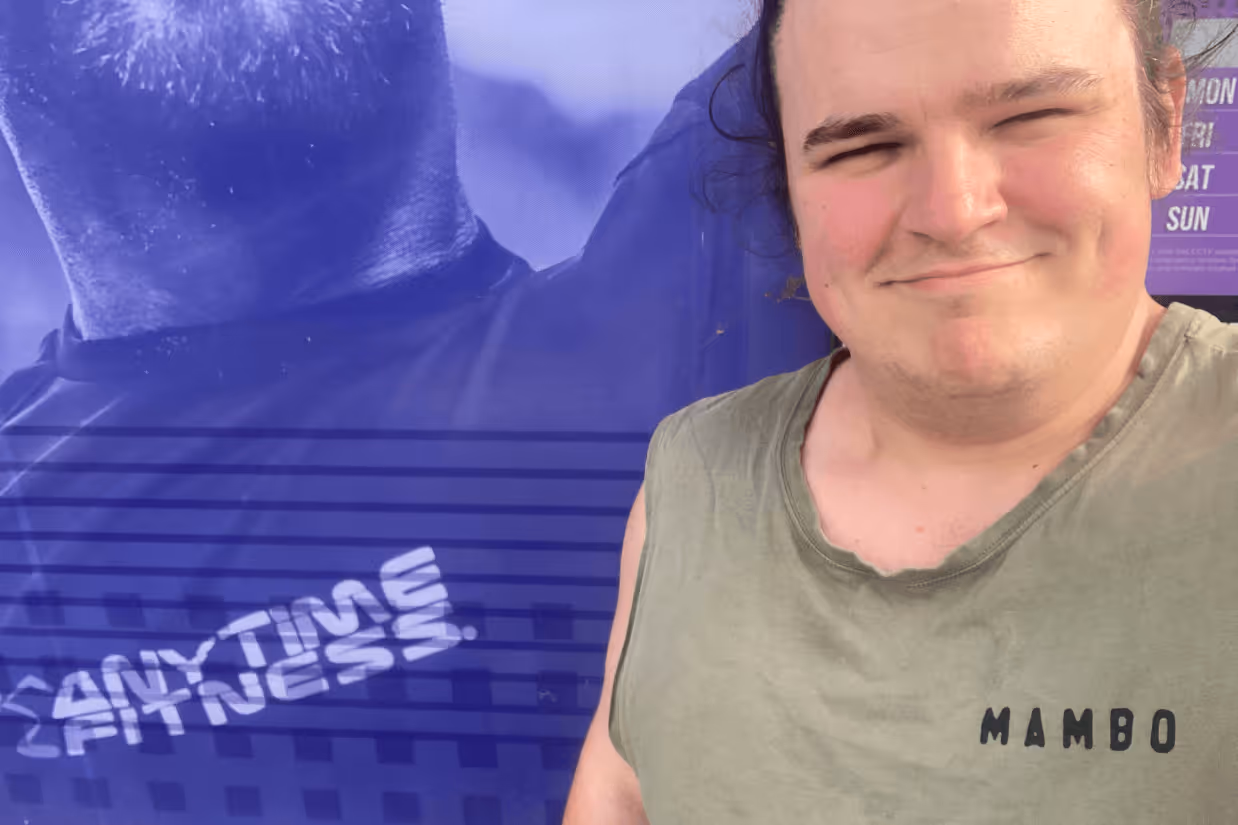 A selfie of an autistic man wearing a khaki singlet outside of a gym.