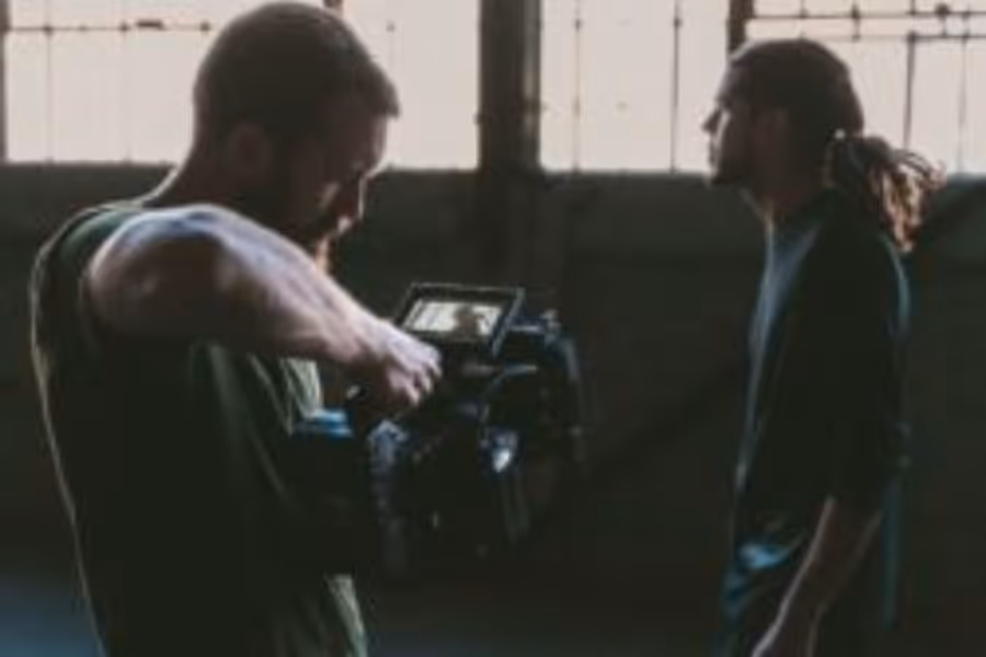 A man filming another man in a warehouse using a handheld camera.