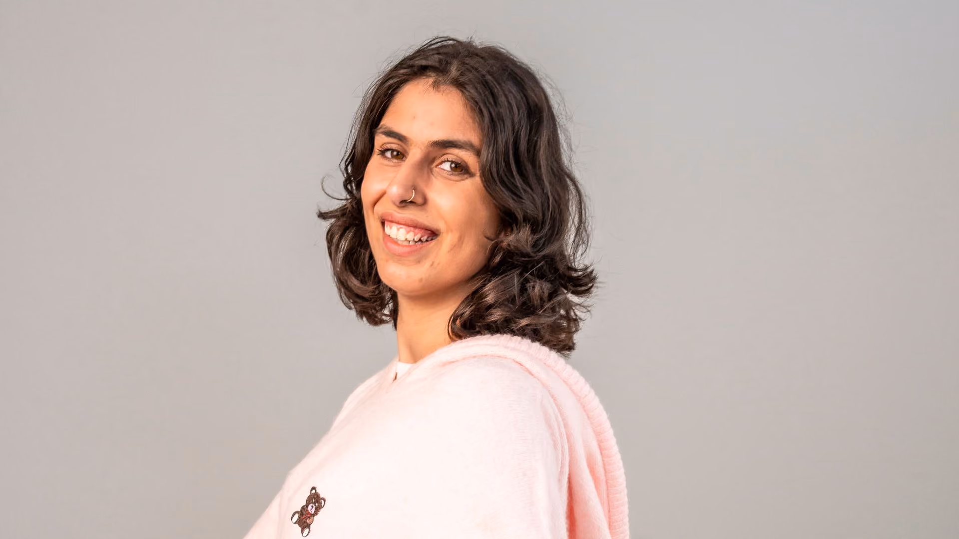 young autistic woman in pink hoody smiling