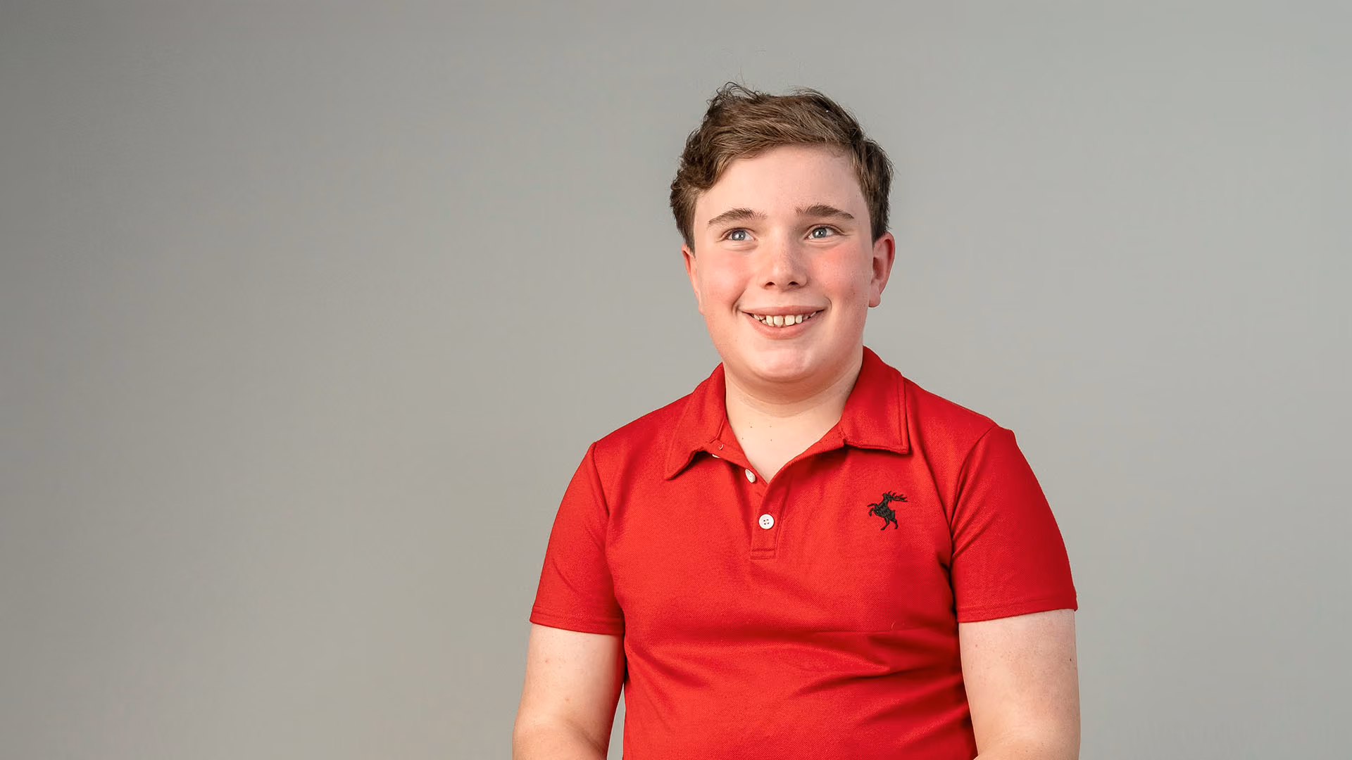 autistic boy wearing red t-shirt and smiling