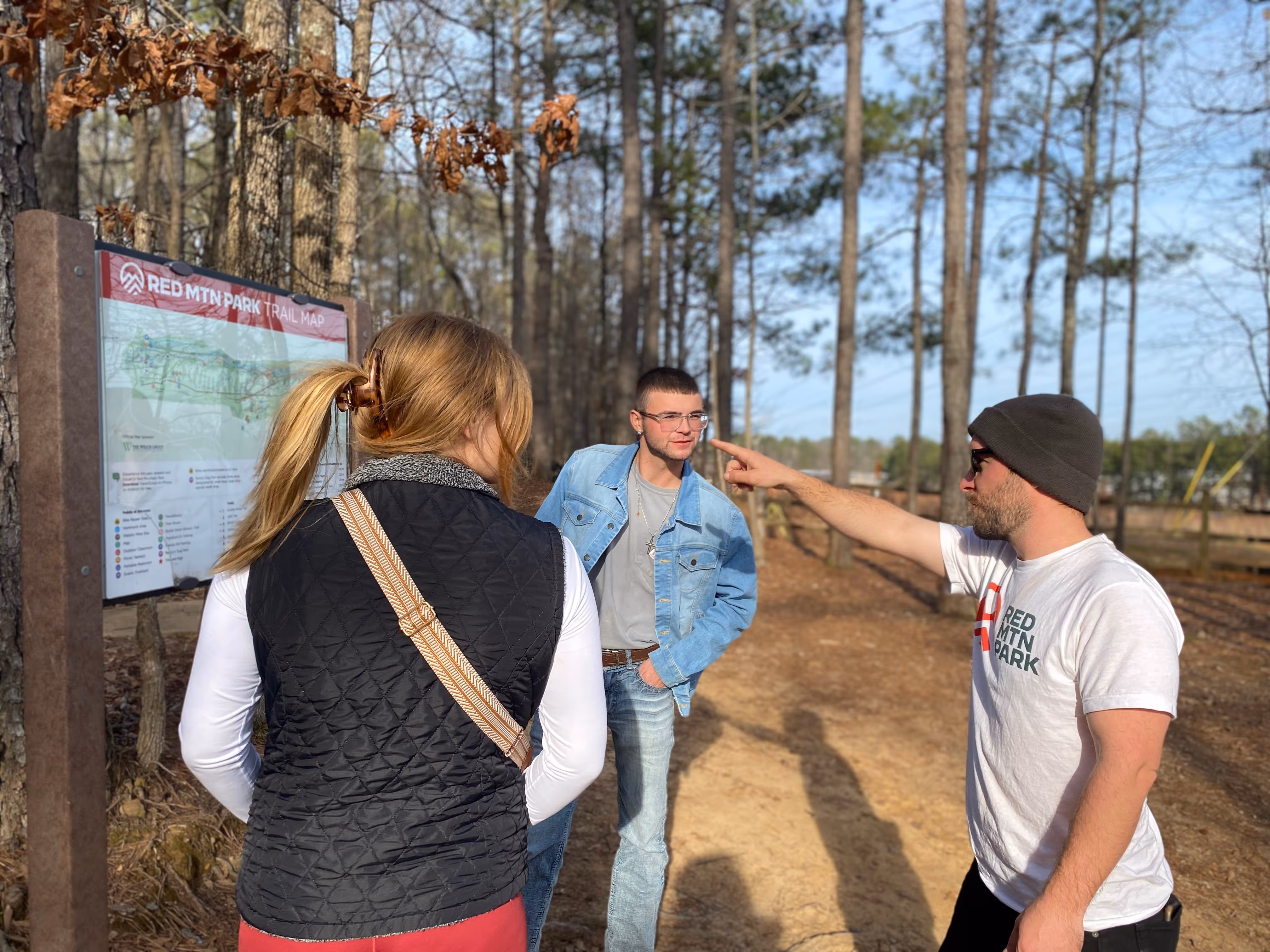 Jefferson County Greenways staff member using a posted map to assist a couple visiting Red Mountain Park 