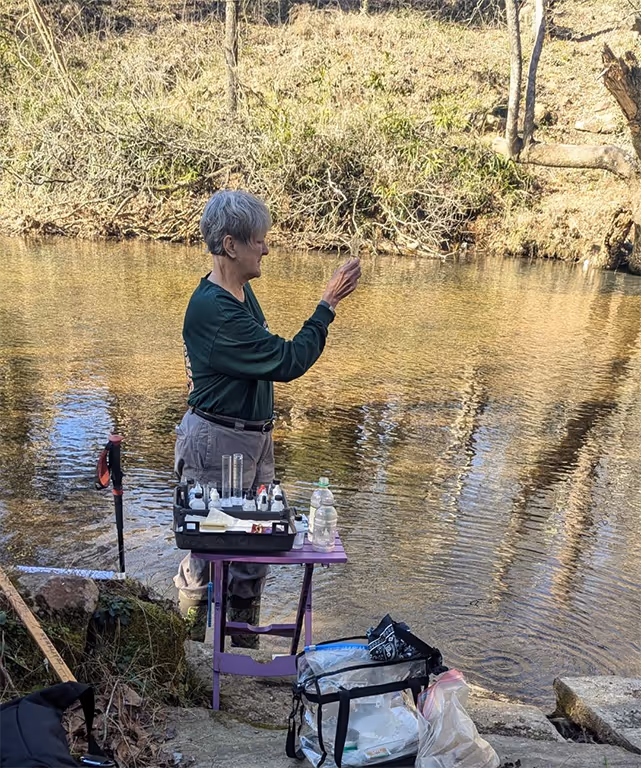 Someone collecting water samples to monitor Turkey Creek