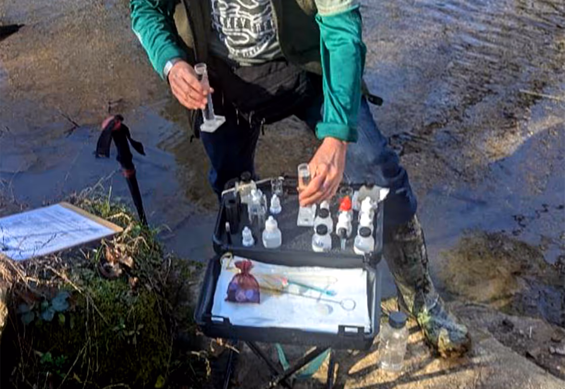 A person taking water samples using a small case with a variety of small bottles and equipment