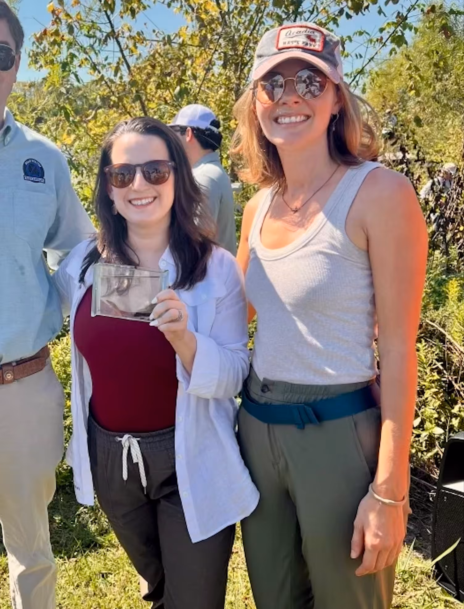 Two women pose for a picture with a small fish
