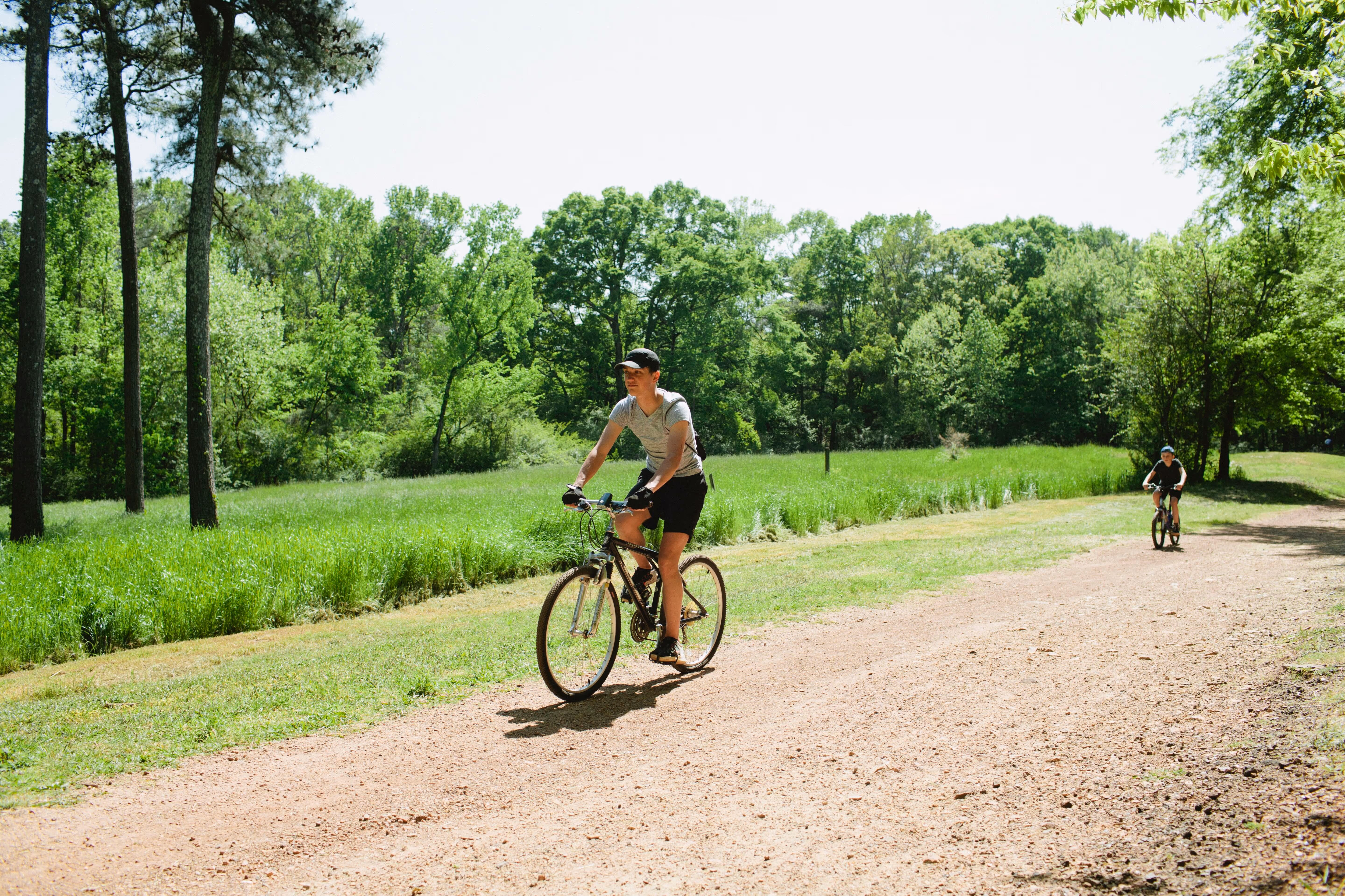 A man biking by a meadow at Red Mountain Park.