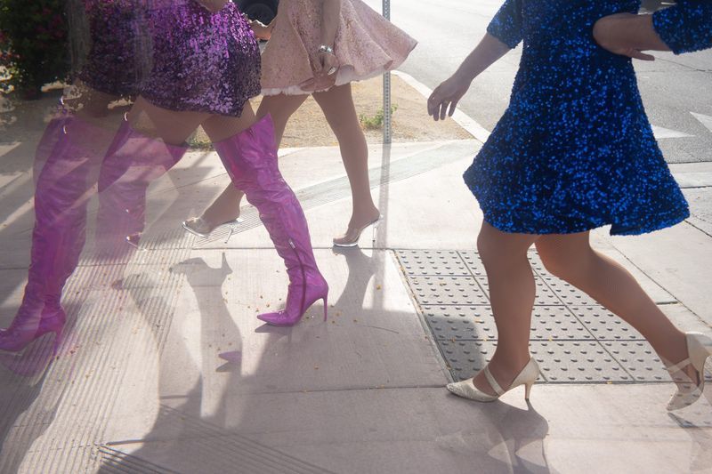 Three Drag & Fly queens in sequins and heels striding across a Palm Springs sidewalk