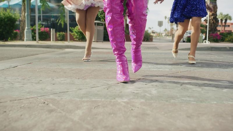 Pink thigh-high boots of a Drag & Fly queen striding toward the camera on a Palm Springs sidewalk