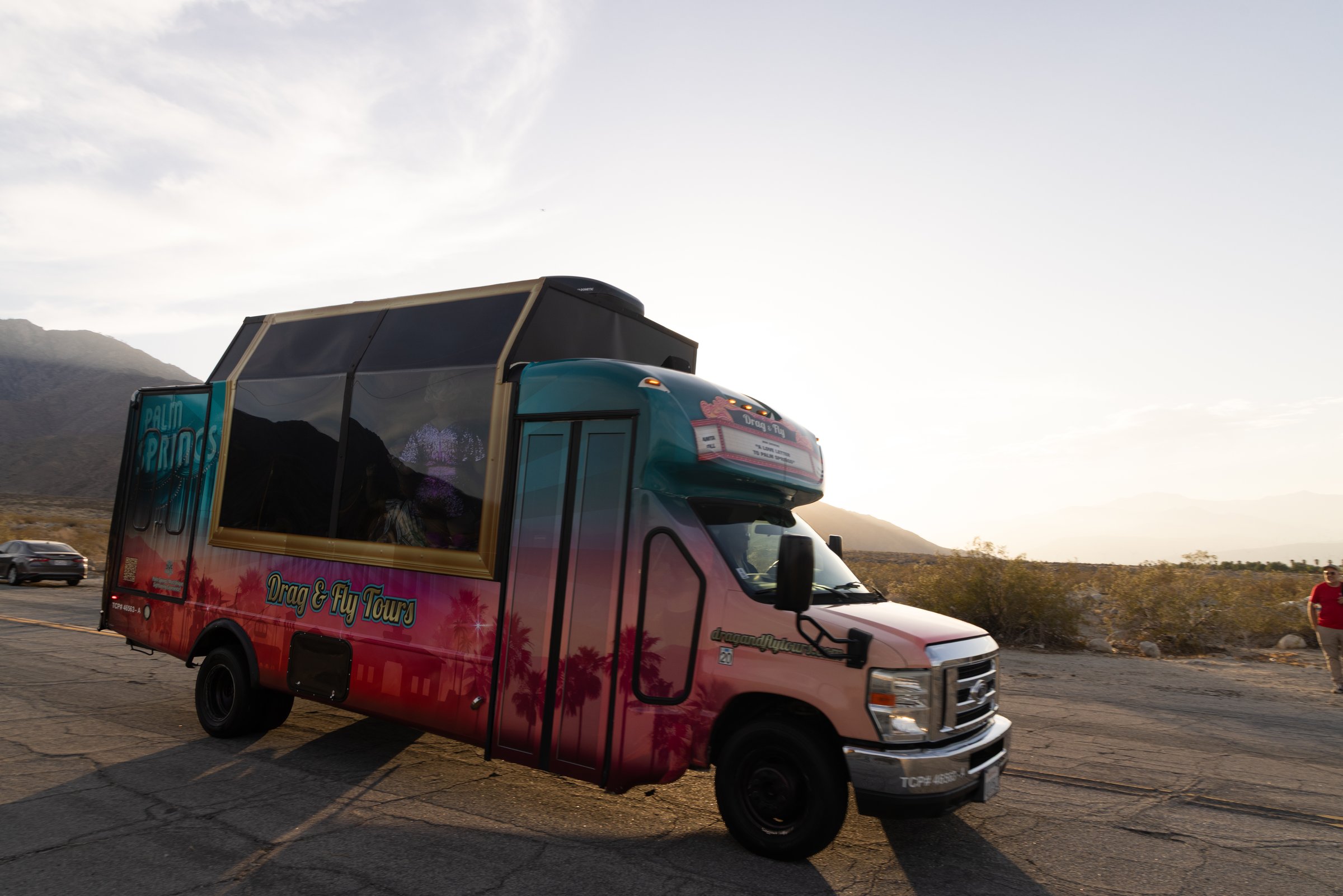 The Drag & Fly Tours bus parked in the desert outside Palm Springs at golden hour