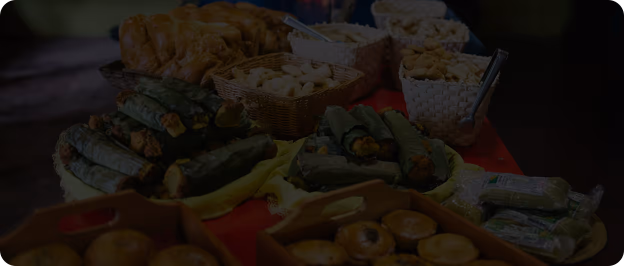 Table filled with various baked goods including bread rolls, pastries, and snack baskets.