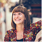 Smiling woman with brown hair and bangs wearing a patterned top.
